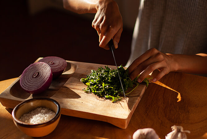 cocinero cortando culantro en una tabla de madera