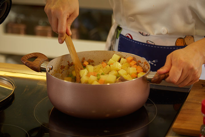 olla con papas y zanahorias cortadas en cuadros junto a la carne y aderezo.