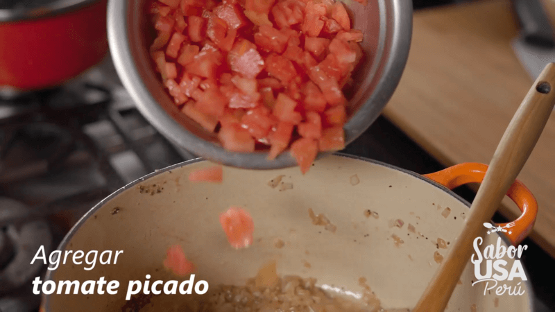 chef agregando tomates picados a la olla